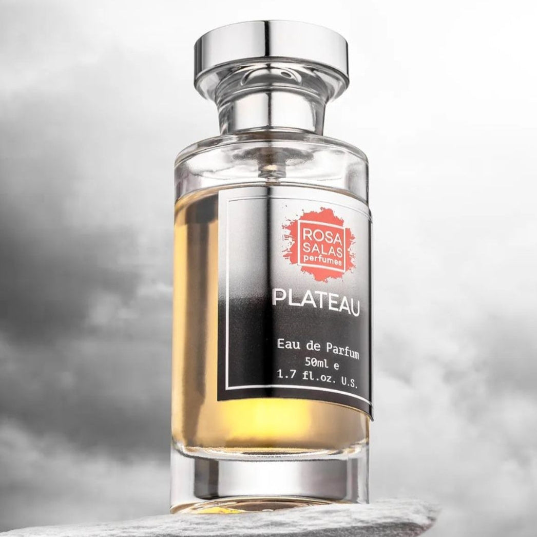 Perfume bottle labeled 'Plateau' by Rosa Salas on a cloudy sky background