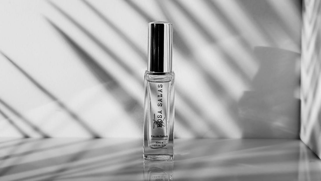 Clear nail polish bottle with black cap on a reflective surface with shadow pattern