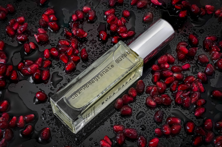 Perfume bottle with pomegranate seeds on a dark surface