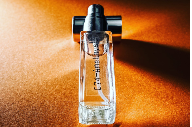 Perfume bottle with a black cap on an orange background