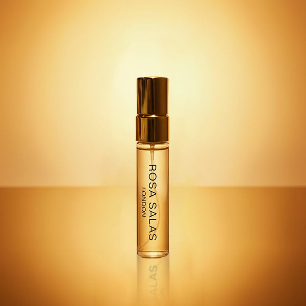 Perfume bottle with gold cap and body on a gradient yellow background